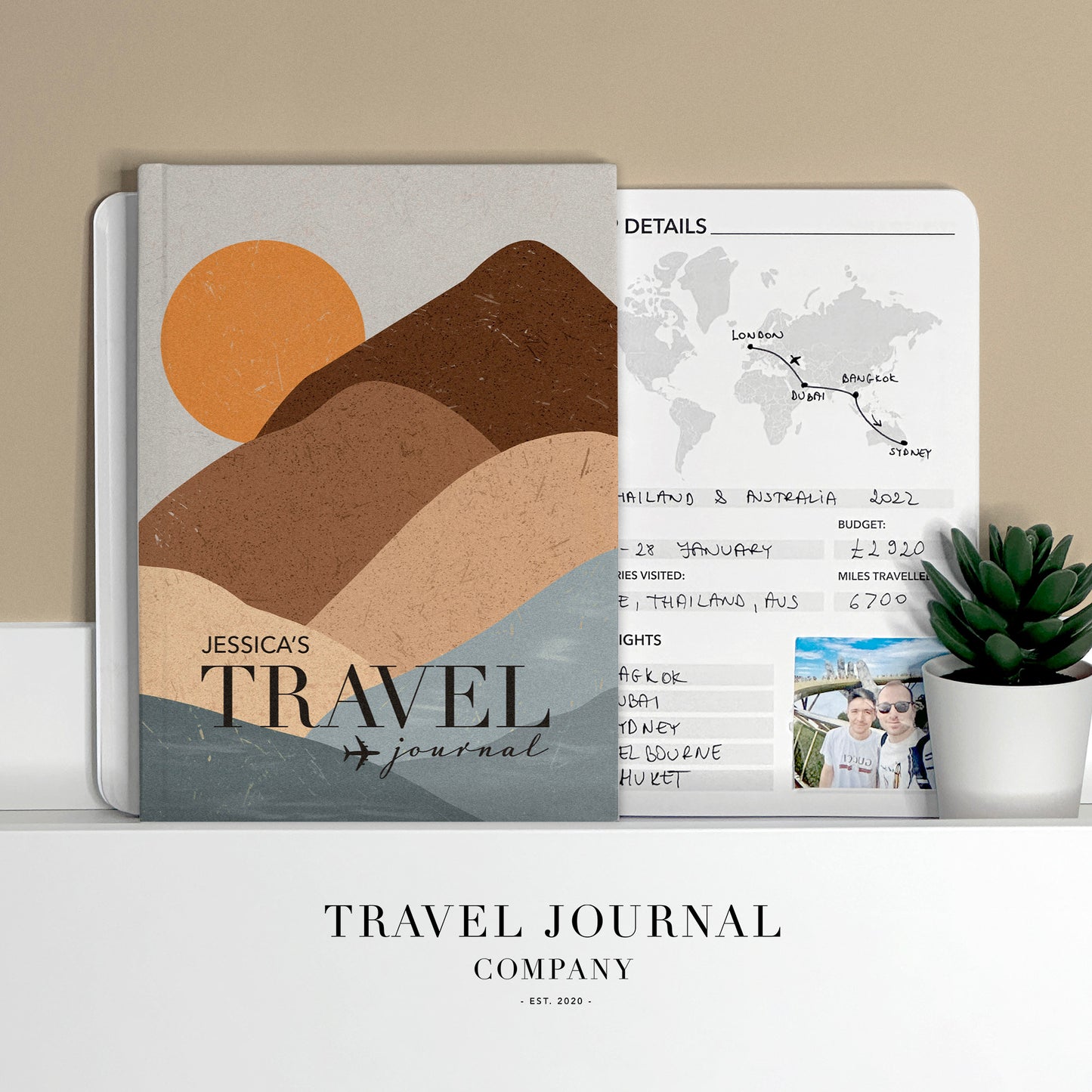 a travel journal sitting on top of a desk next to a plant