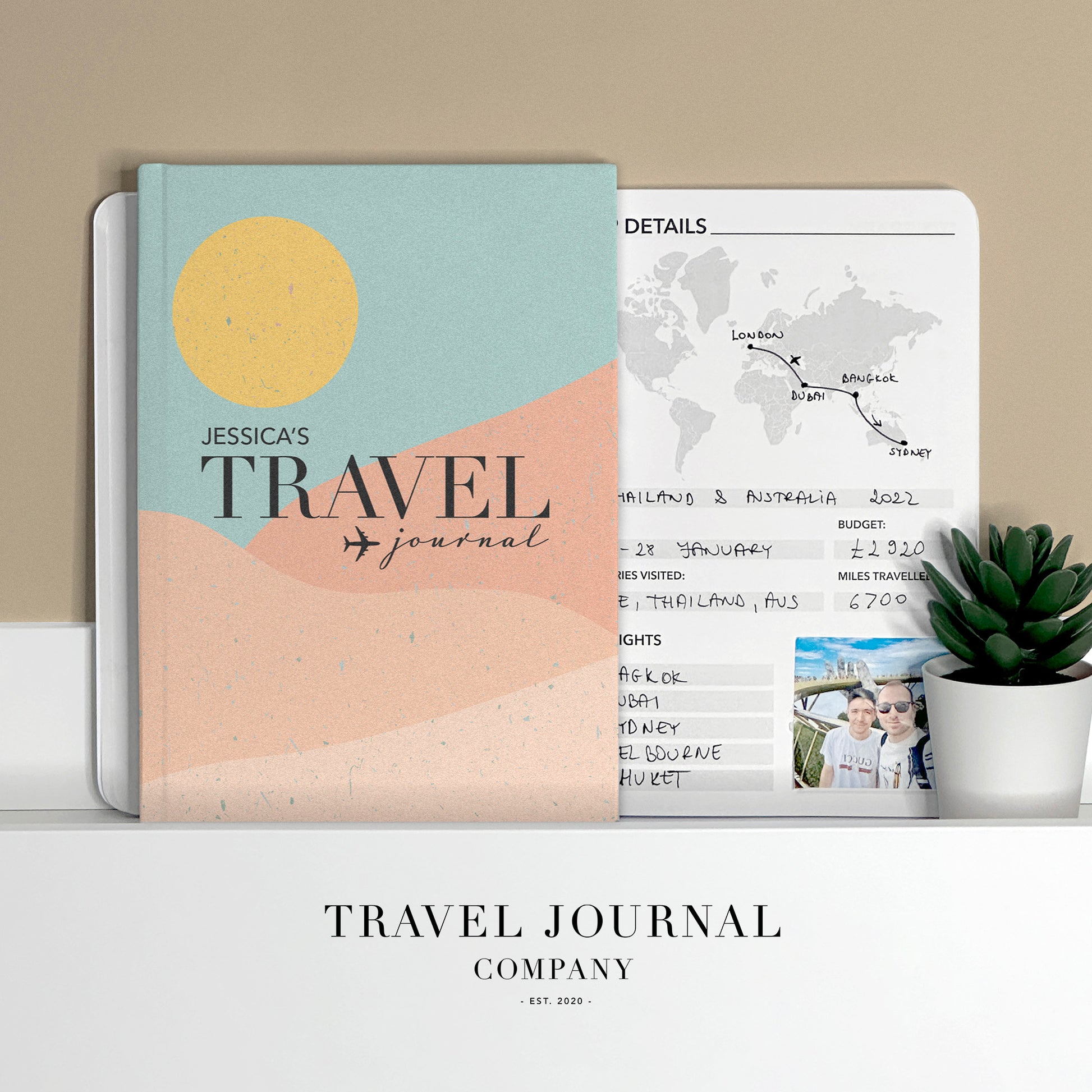 a travel journal sitting on top of a desk next to a potted plant