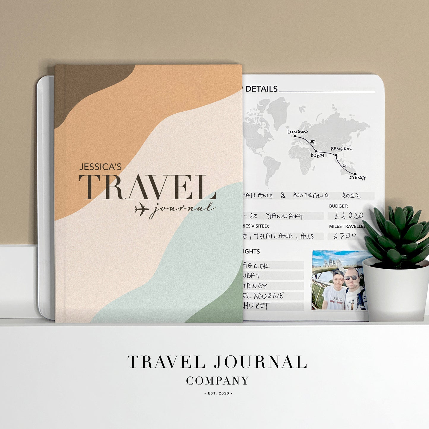 a travel journal sitting on top of a desk next to a potted plant